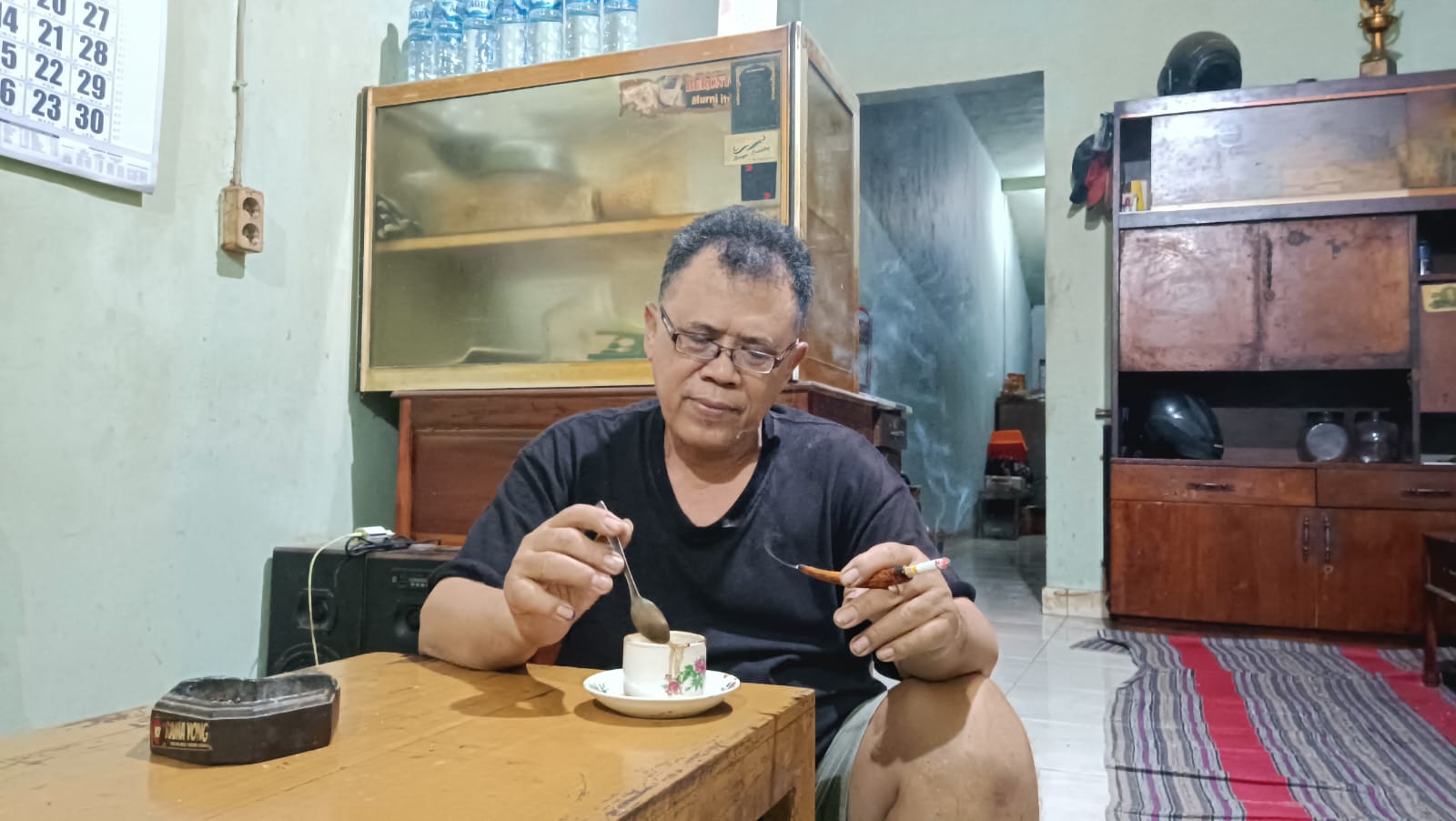 Pak B, pemilik warung kopi Komunitas Pecandu Kopi (KPK) menikmati kopi buatannya sendiri. KBRT